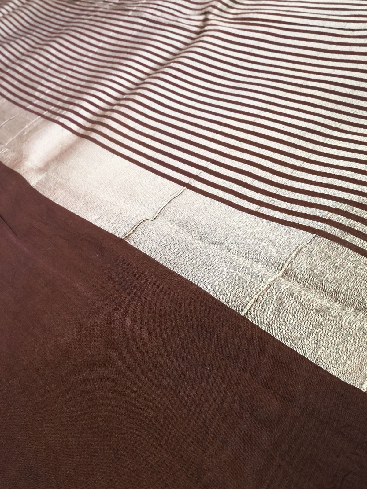 Close detail of the striped gold pallu against coffee brown silk