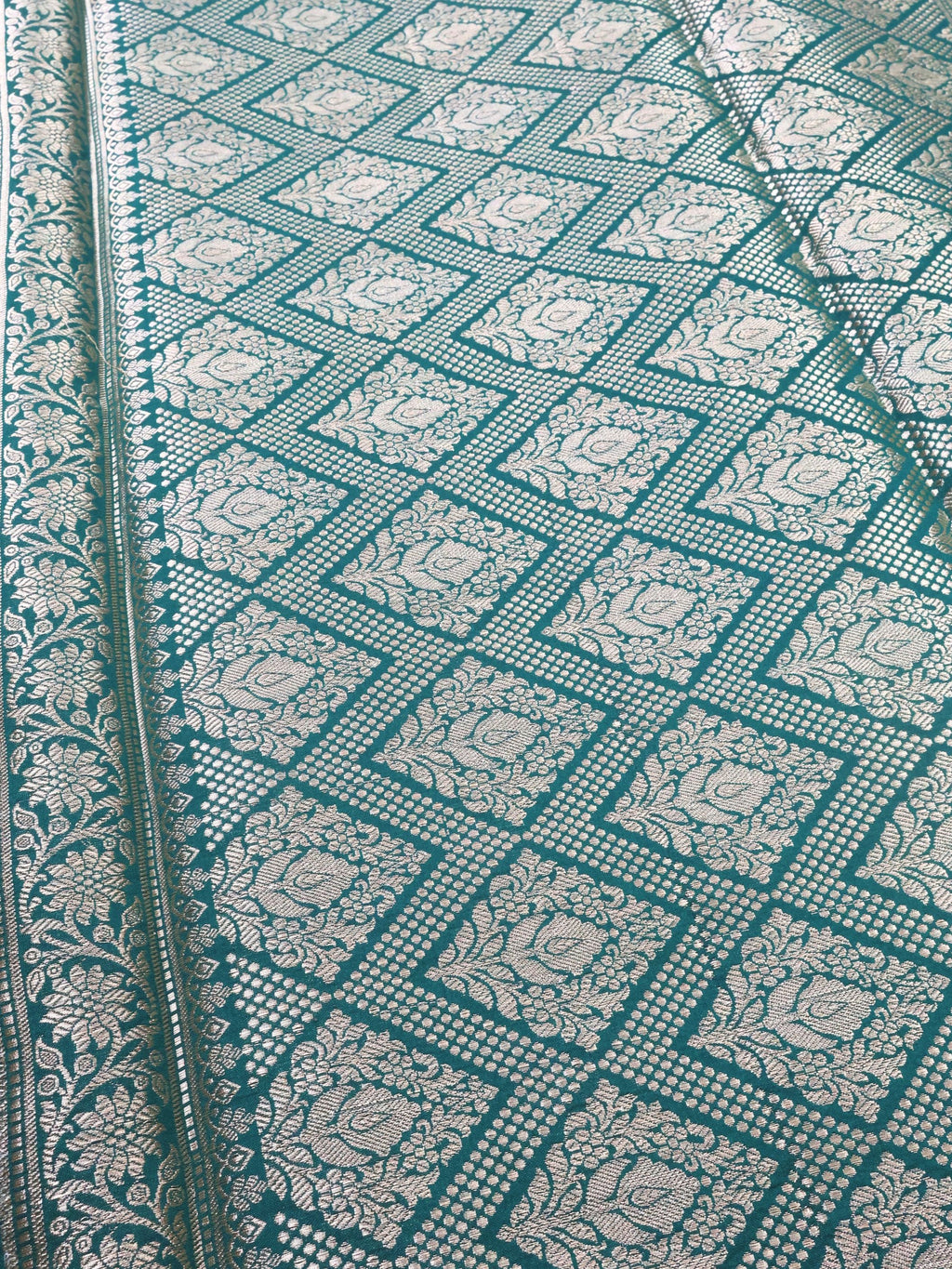 Close detail of the silver zari lattice on deep green silk