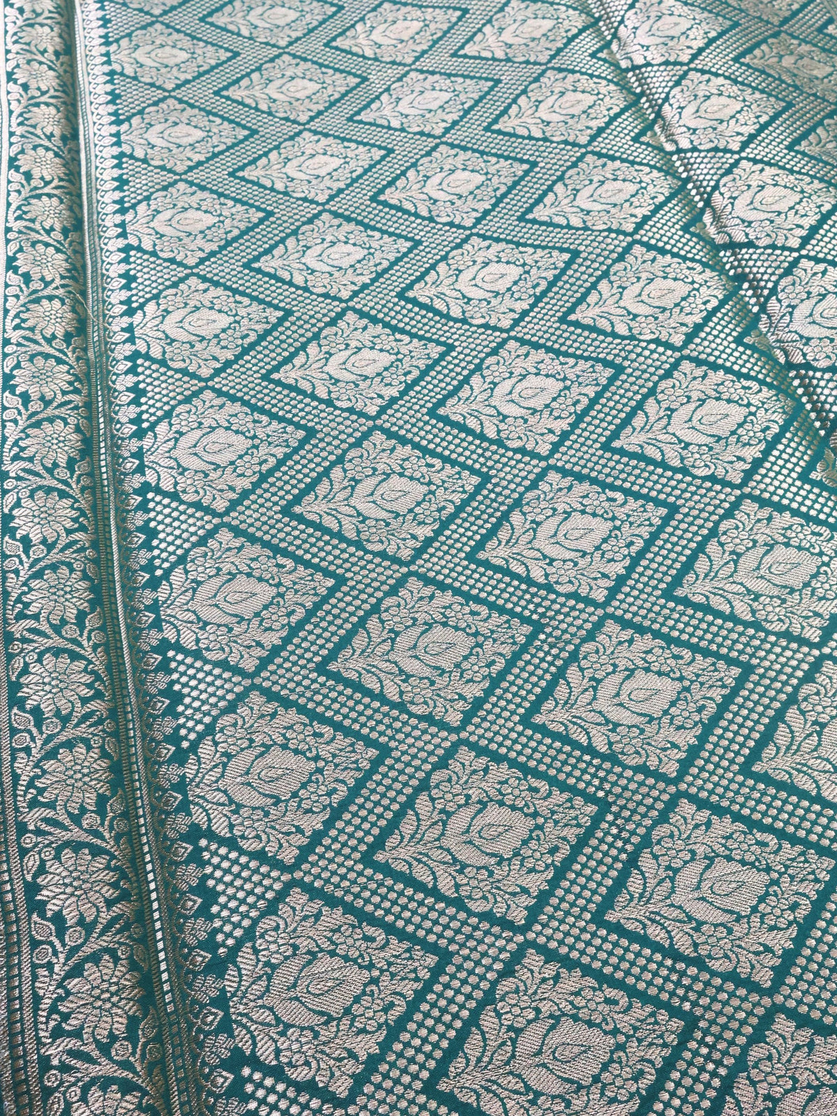Close detail of the silver zari lattice on deep green silk