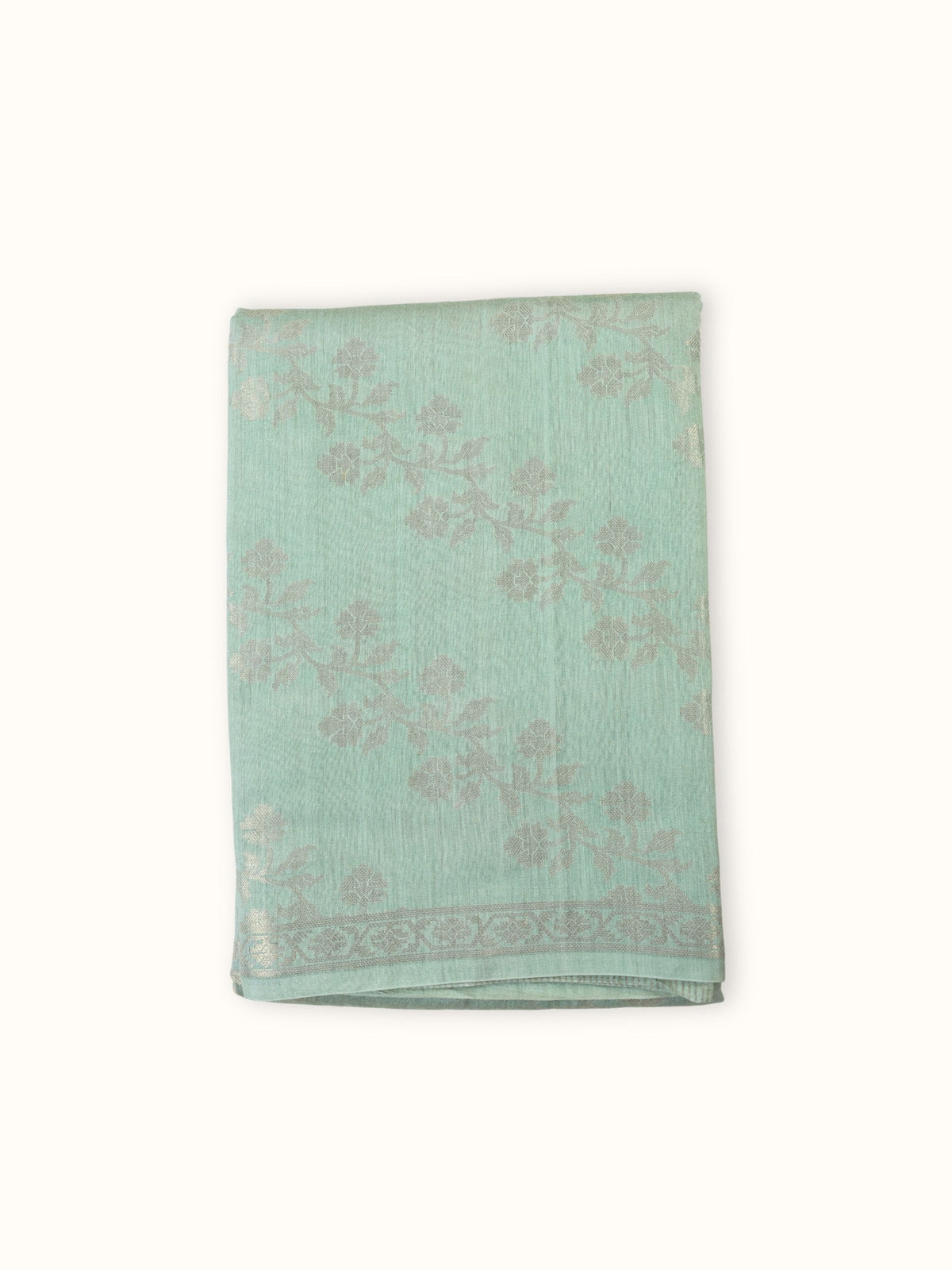 Pale aqua Muga silk saree folded, with gold floral sprays